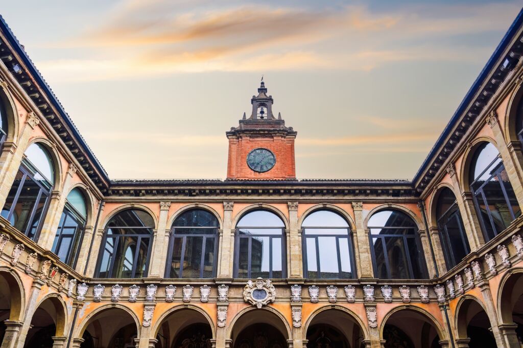 Bologna, Italy Biblioteca Comunale dell'Archiginnasio courtyard with clock tower against sky.